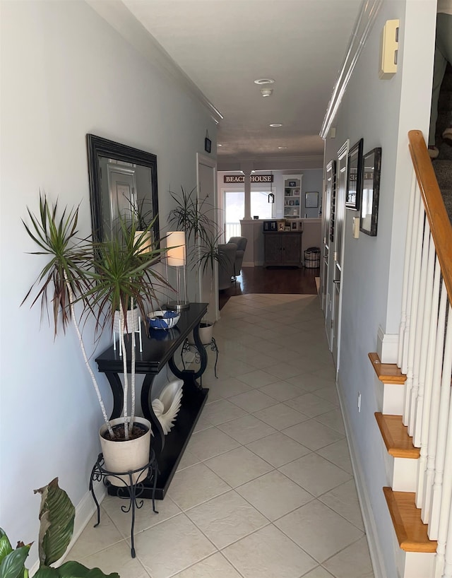 hallway with ornamental molding and light tile patterned floors