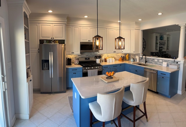 kitchen with appliances with stainless steel finishes, a center island, pendant lighting, white cabinetry, and blue cabinets