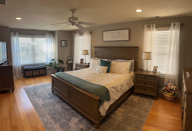 bedroom featuring wood-type flooring, multiple windows, and ceiling fan