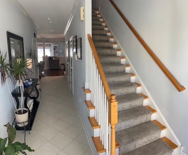 staircase with ornamental molding and tile patterned flooring