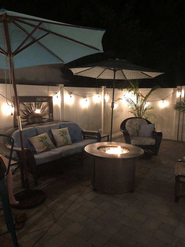 patio at twilight featuring an outdoor living space with a fire pit