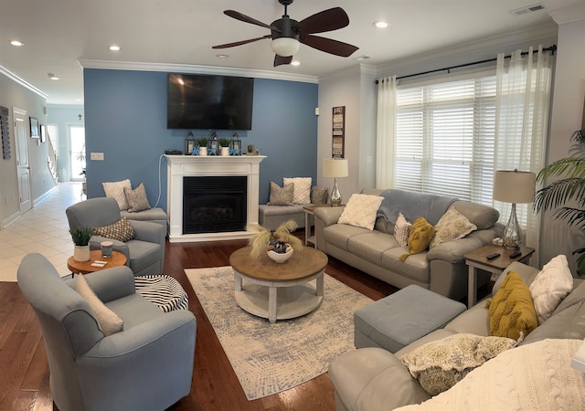 living room with dark wood-type flooring, ceiling fan, and crown molding