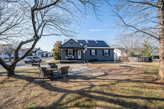 bungalow-style home with roof mounted solar panels and a front yard