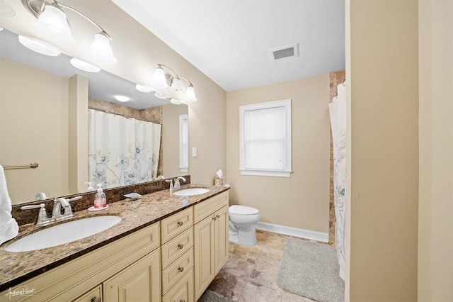 full bathroom featuring toilet, a sink, visible vents, and baseboards