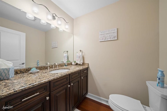 half bathroom featuring toilet, baseboards, wood finished floors, and vanity