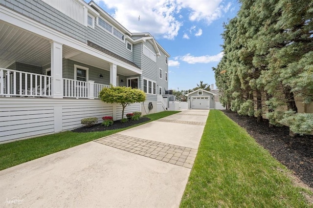 exterior space with concrete driveway, a porch, an outdoor structure, and a detached garage