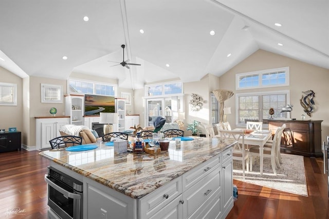 kitchen featuring dark wood-type flooring, light stone countertops, oven, and white cabinets