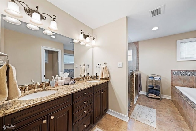 full bath with double vanity, tiled bath, a sink, and visible vents