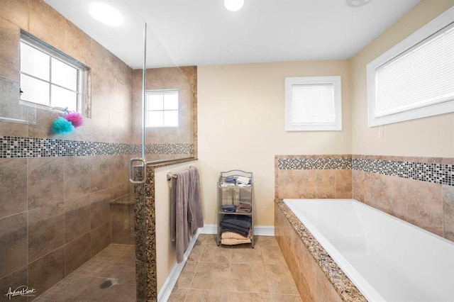 bathroom featuring a stall shower, a garden tub, baseboards, and tile patterned floors