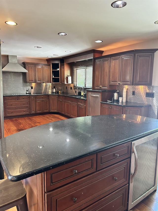 kitchen featuring sink, tasteful backsplash, a breakfast bar area, and wall chimney range hood