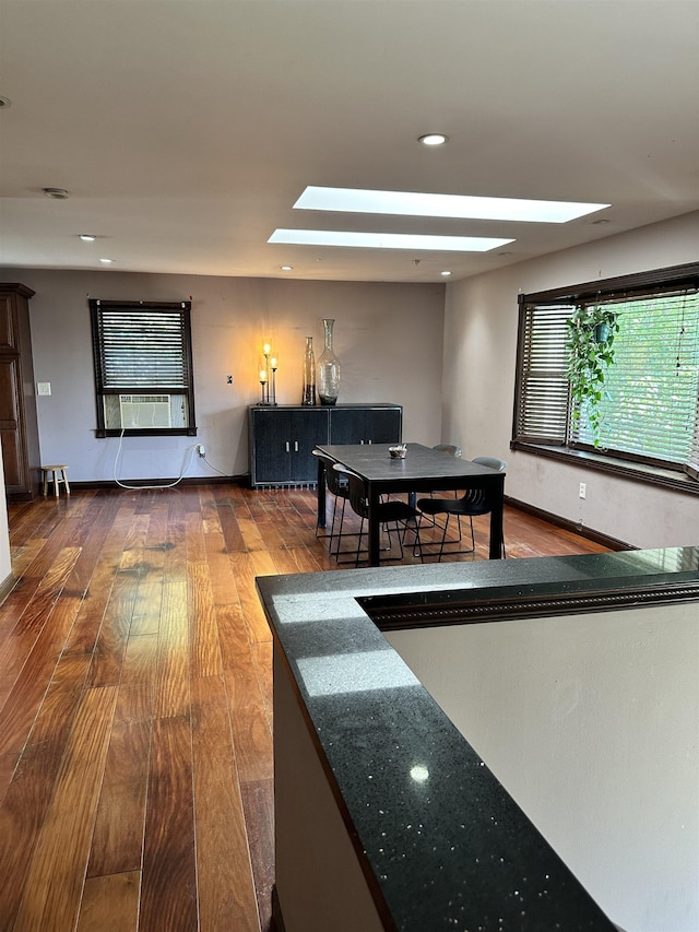 interior space with cooling unit, wood-type flooring, and a skylight