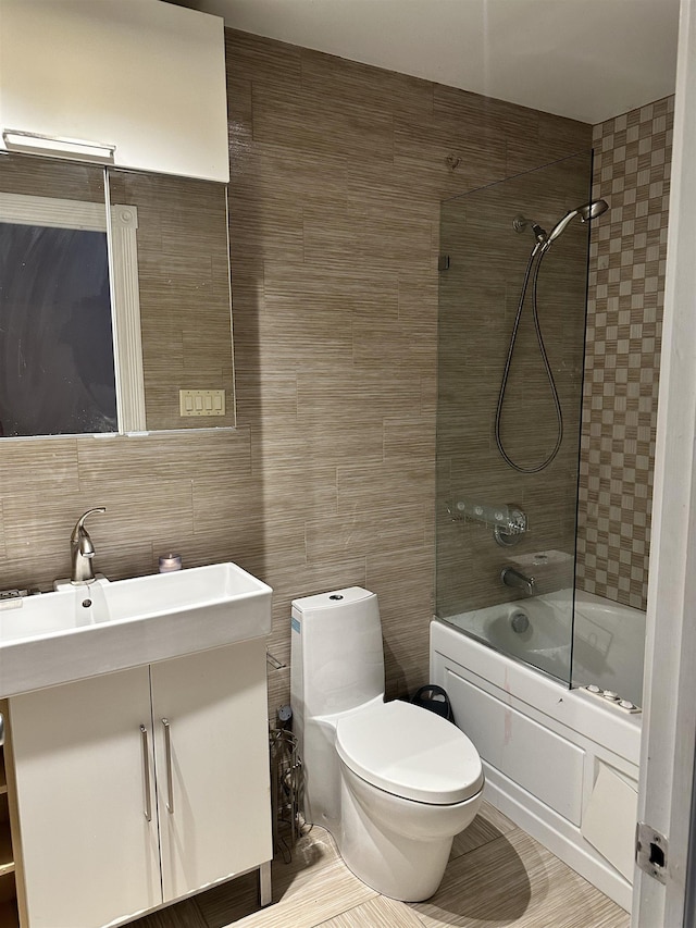 full bathroom featuring vanity, tiled shower / bath combo, toilet, tile walls, and tasteful backsplash