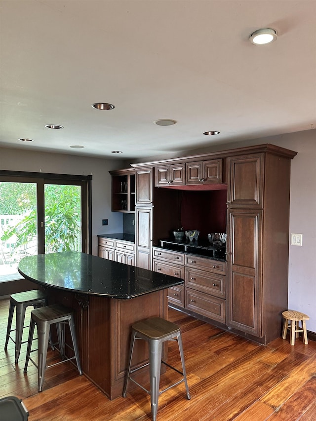 kitchen featuring a kitchen bar, dark brown cabinets, a center island, and dark hardwood / wood-style floors