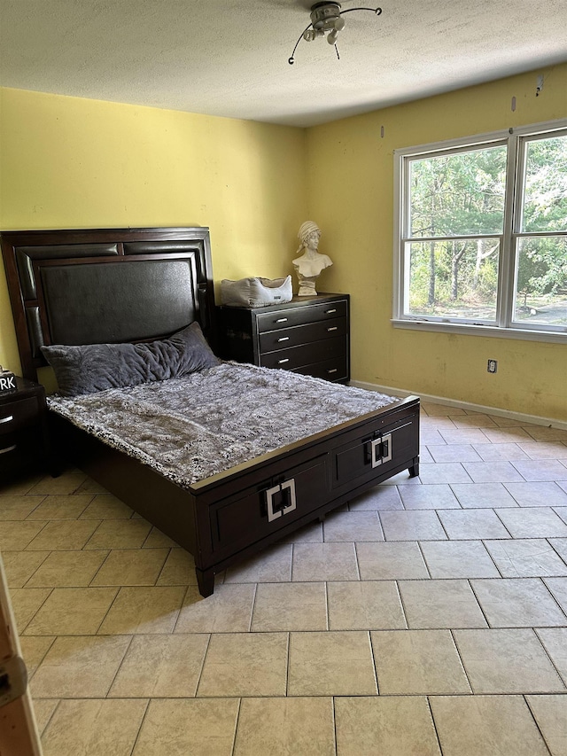 tiled bedroom featuring a textured ceiling and ceiling fan