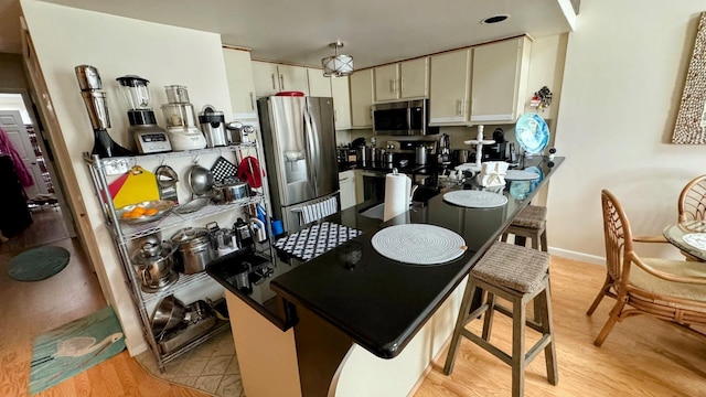 kitchen with stainless steel appliances, light wood-type flooring, and kitchen peninsula