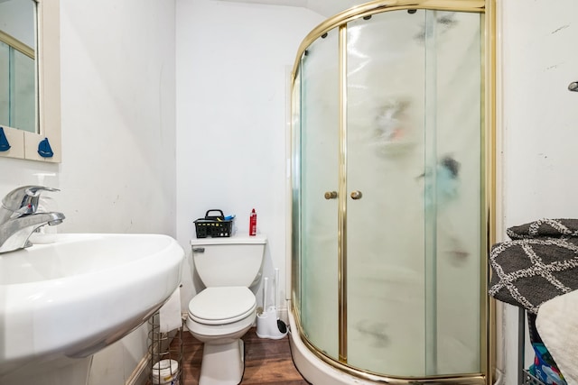 bathroom featuring toilet, a stall shower, a sink, and wood finished floors