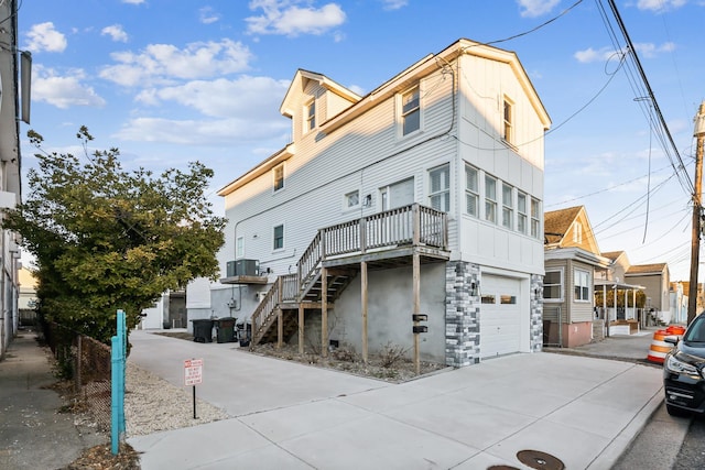 exterior space featuring a garage, concrete driveway, central AC unit, and stairway