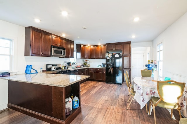 kitchen featuring a peninsula, light stone countertops, stainless steel appliances, light wood-style floors, and recessed lighting