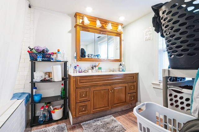 bathroom with a soaking tub, wood finished floors, and vanity