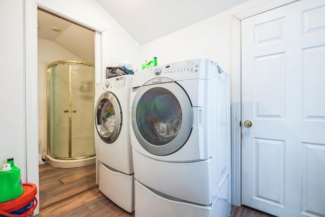 clothes washing area with dark wood-style floors, washer and dryer, and laundry area