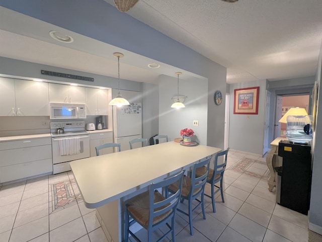 kitchen with pendant lighting, white appliances, white cabinets, light tile patterned floors, and a kitchen bar