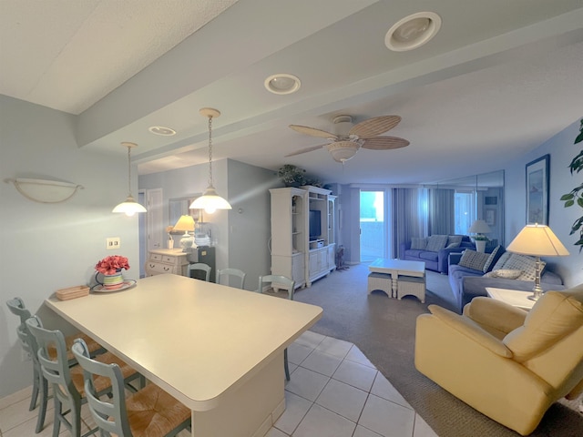 kitchen featuring a breakfast bar, hanging light fixtures, ceiling fan, light tile patterned floors, and kitchen peninsula