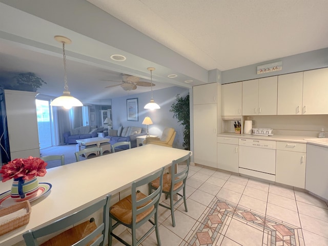 kitchen with white dishwasher, ceiling fan, light tile patterned floors, white cabinets, and hanging light fixtures