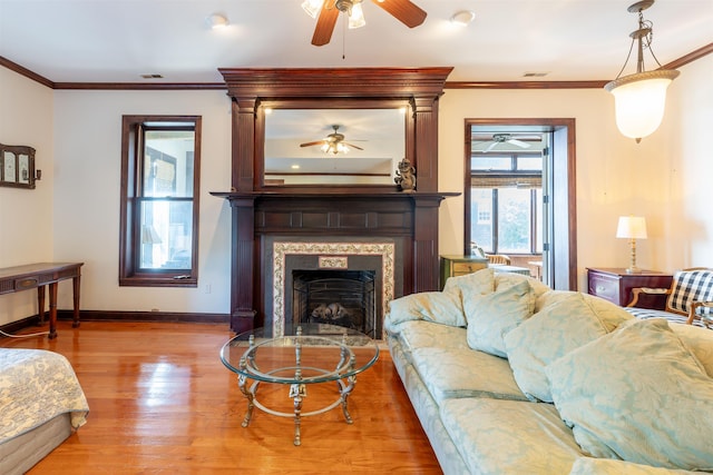 living room featuring a fireplace, light wood-type flooring, and crown molding