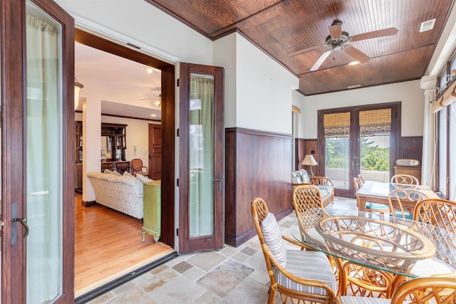 dining room featuring ceiling fan, french doors, crown molding, wooden walls, and wood ceiling