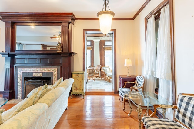 living area with crown molding, light hardwood / wood-style flooring, and a high end fireplace