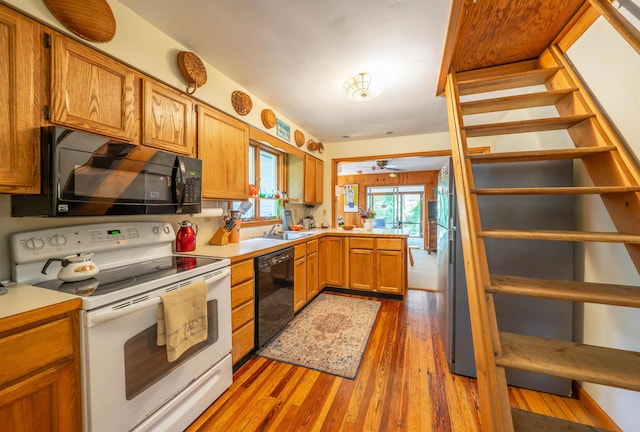 408 Princeton Ave, Cape May Point, NJ 08212 - kitchen featuring black appliances, a peninsula, wood finished floors, light countertops, and brown cabinetry