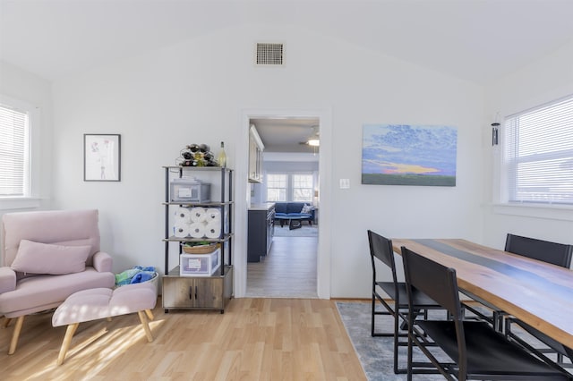 dining room with light wood-style floors, visible vents, and vaulted ceiling