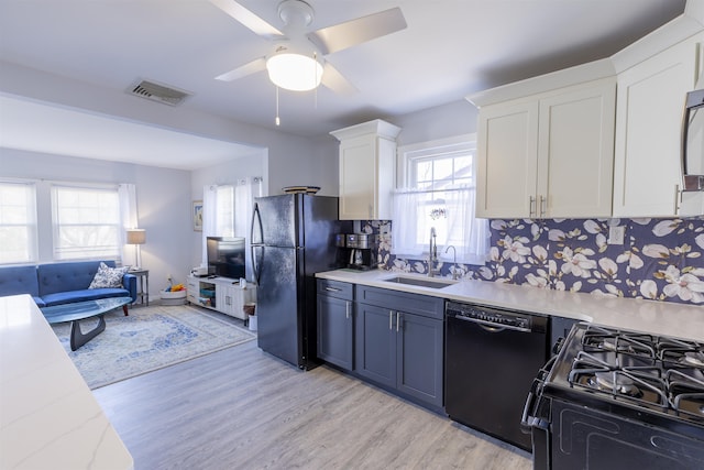 kitchen featuring a sink, visible vents, white cabinetry, black appliances, and light wood finished floors