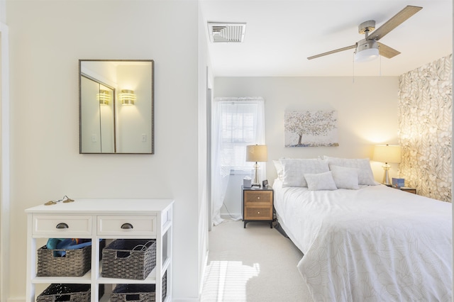 bedroom featuring a ceiling fan, visible vents, and light colored carpet