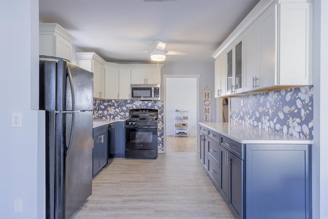 kitchen with light countertops, decorative backsplash, glass insert cabinets, white cabinetry, and black appliances