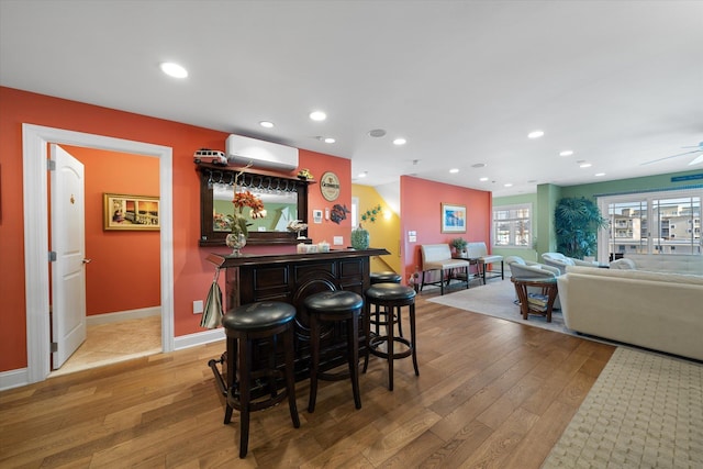 bar featuring hardwood / wood-style floors, ceiling fan, and a wall mounted AC