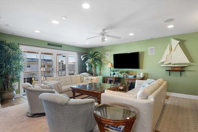 living room featuring ceiling fan, a fireplace, and light hardwood / wood-style floors