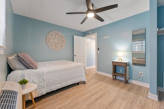 bedroom with light wood-style floors, multiple windows, baseboards, and a ceiling fan