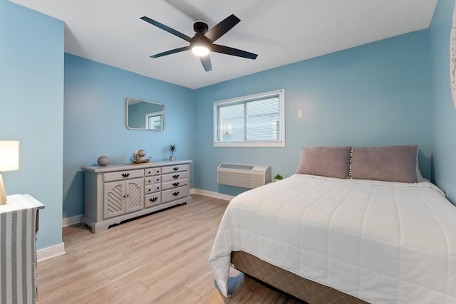 bedroom with an AC wall unit, ceiling fan, light wood-style flooring, and baseboards