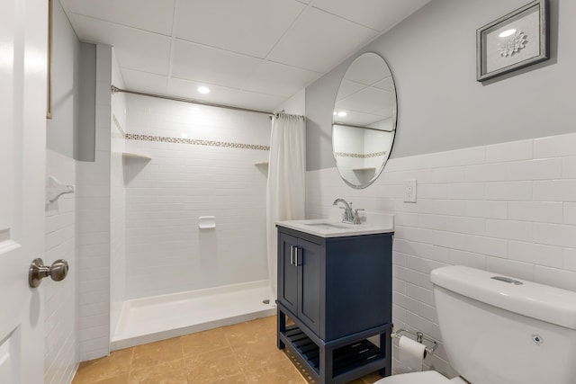 full bathroom featuring tile walls, toilet, a tile shower, vanity, and tile patterned floors