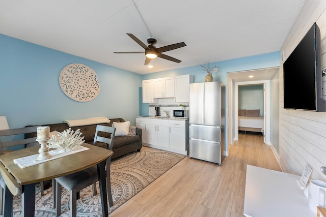 living area featuring light wood-style floors and a ceiling fan