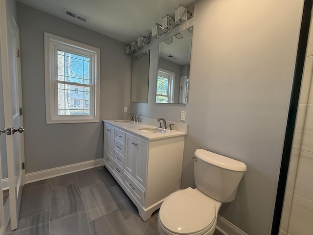 bathroom featuring toilet, a sink, and visible vents