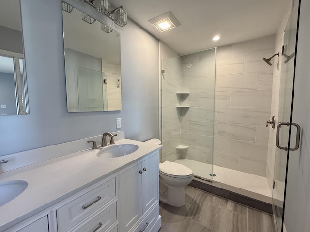 bathroom featuring a stall shower, a sink, toilet, and double vanity