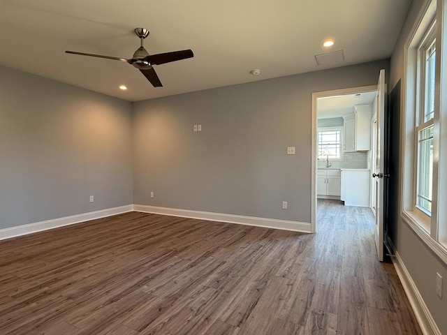 spare room featuring ceiling fan, recessed lighting, a sink, baseboards, and dark wood-style floors