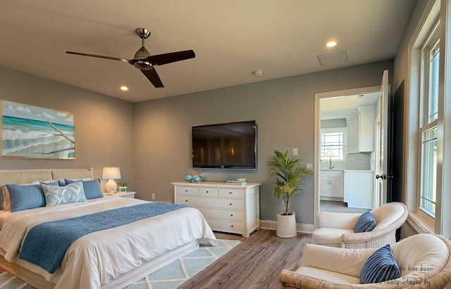 bedroom featuring baseboards, recessed lighting, ensuite bath, and light wood-style floors