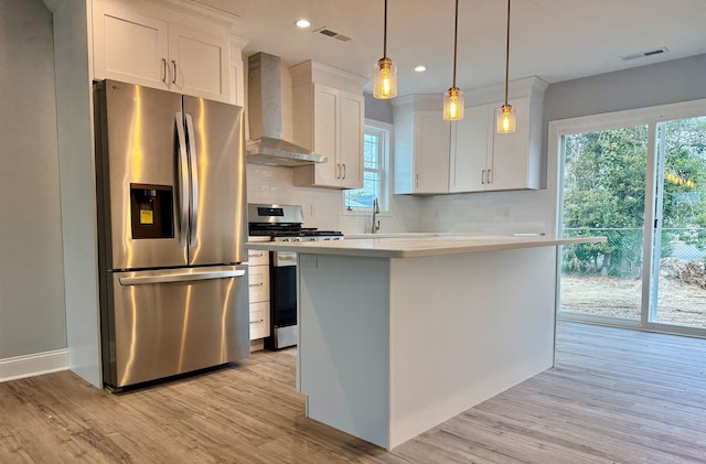 kitchen featuring visible vents, light countertops, appliances with stainless steel finishes, wall chimney range hood, and backsplash