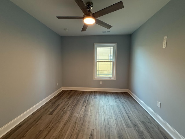 unfurnished room featuring a ceiling fan, dark wood-style flooring, visible vents, and baseboards