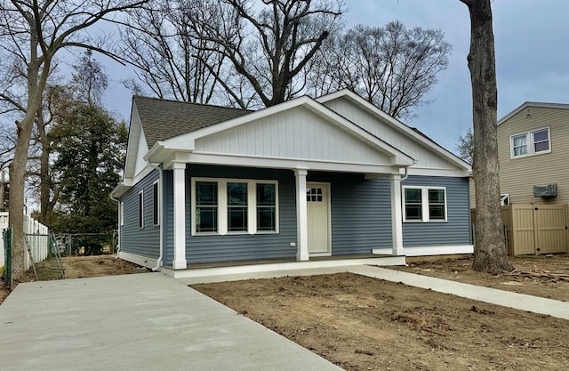 view of front of house featuring a porch, fence, and a shingled roof