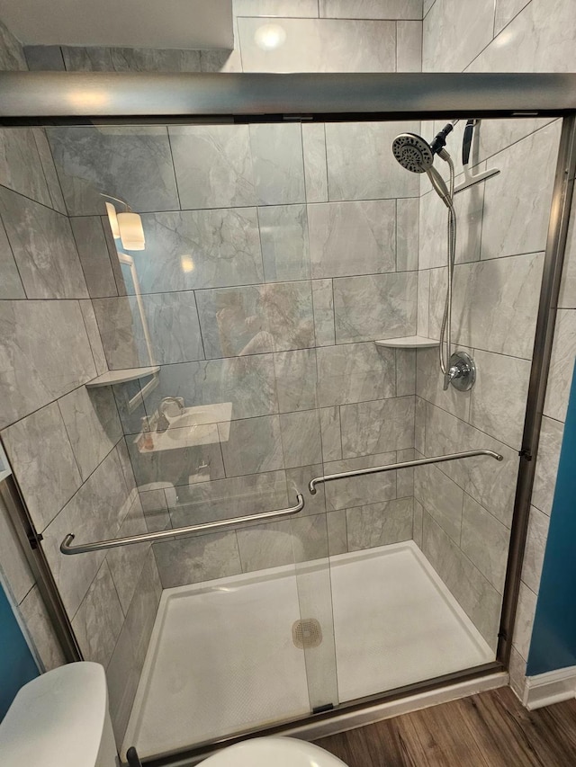 bathroom featuring hardwood / wood-style flooring, toilet, and a shower with shower door