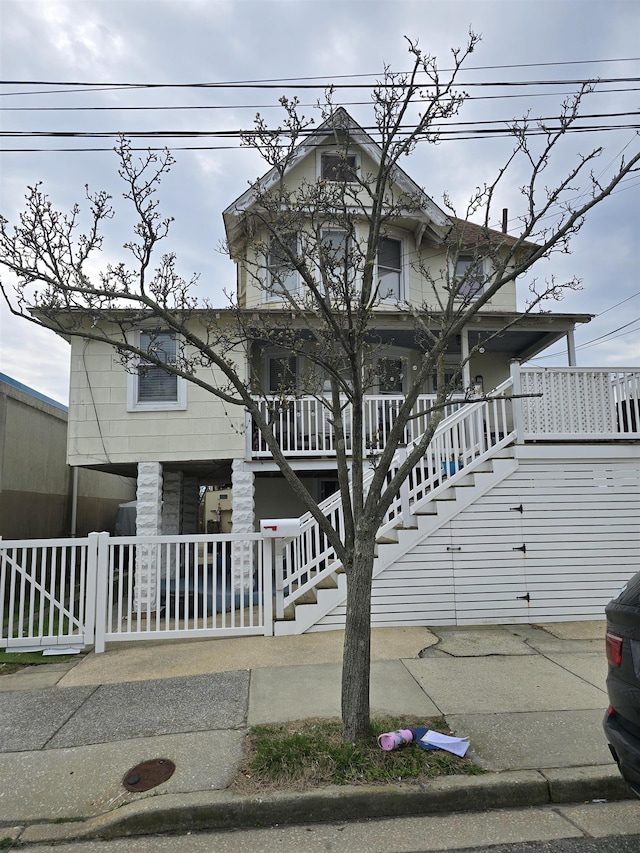 view of front facade with a porch, stairway, and fence
